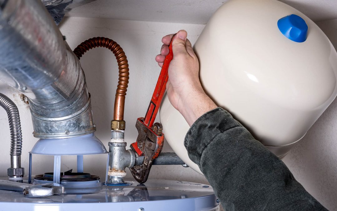 Plumber Works On Water Heater With A Pipe Wrench